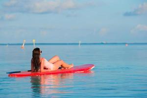 donna che si distende su una tavola da surf foto