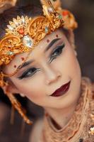 avvicinamento viso di un asiatico donna nel trucco indossare oro corona e oro Accessori con bellissimo facce foto