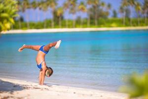 ragazza che fa una ruota di carro su una spiaggia foto