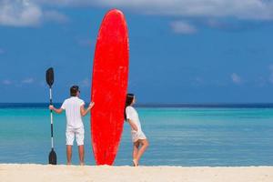 coppia con un paddleboard in spiaggia foto