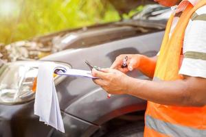 avvicinamento e Ritaglia assicurazione agente scrittura su appunti mentre l'esame auto dopo incidente Richiesta essere valutato e elaborato su sole bagliore e sfocato sfondo. foto