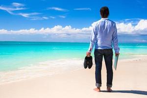 uomo con laptop e scarpe in spiaggia foto