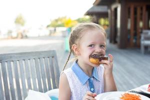 ragazza che mangia una ciambella foto