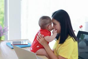 giovane mamma asiatica che lavora da casa foto