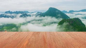 pavimento in legno naturale, vista sulle montagne e nebbia mattutina foto