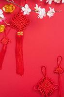 concetto di design del capodanno lunare cinese - bellissimo nodo cinese con fiore di prugna isolato su sfondo rosso, disposizione piatta, vista dall'alto, disposizione aerea. foto