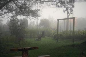 terreno di gioco nel nebbia con nebbia. Fata spaventoso guardare boschi nel un' nebbioso giorno. freddo nebbioso mattina nel orrore terreno di gioco con alberi. vuoto figli di terreno di gioco su un' nebbioso autunno mattina. foto