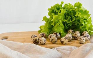 azienda agricola Quaglia uova su un' di legno cucina tavola con verde lattuga lascia.il concetto di corretto salutare cibo. foto