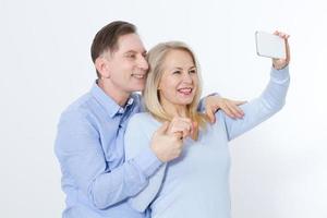 contento coppia assunzione autoscatto con smartphone isolato su bianca foto
