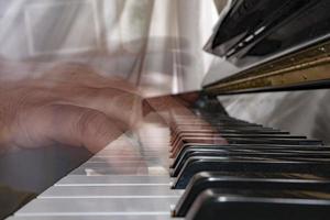 mani giocando pianoforte mentre in movimento foto