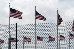 agitando Stati Uniti d'America bandiere dietro a recinto griglia foto