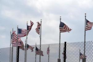 agitando Stati Uniti d'America bandiere dietro a recinto griglia foto