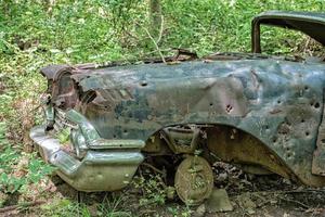 vecchio arrugginito auto abbandonato nel foresta con pistola proiettile fori foto