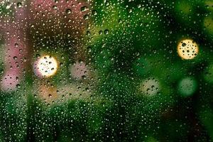 gocce di pioggia sulla finestra con bokeh colorato foto