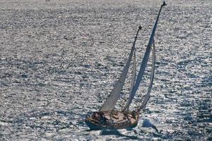 un' regata di legno nave con solitario Capitano andare in barca nel il blu mare foto