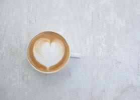 tazza di latte con forma di cuore sul tavolo bianco foto