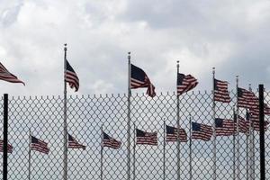 agitando Stati Uniti d'America bandiere dietro a recinto griglia foto