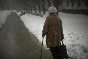 donna con a piedi bastone. pensionato passeggiate giù strada. nonna su strada nel Russia. foto