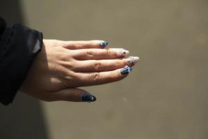 bellissimo Chiodi di ragazza. manicure su dita. blu Chiodi con ciottoli. foto