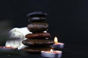 pila di fortunato pietre nel buio sfondo, con 2 ardente candele Usato per rilassante concetti come yoga, massaggio concetto di sfondo e manifesto design. foto