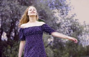 contento giovane ragazza nel un' romantico vestito su un' verde estate prato. bellissimo adolescente ragazza sorrisi e sembra in il telecamera. foto