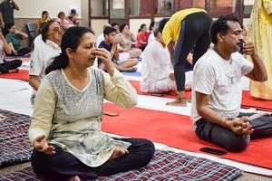 nuova delhi, india, 19 giugno 2022 -sessione di esercizi di yoga di gruppo per persone di diverse età nel tempio di balaji, vivek vihar, giornata internazionale di yoga, grande gruppo di adulti che frequentano lezioni di yoga nel tempio foto