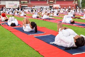 nuovo delhi, India, giugno 21 2022 - gruppo yoga esercizio sessione per persone a yamuna gli sport complesso nel delhi su internazionale yoga giorno, grande gruppo di adulti frequentando yoga classe nel cricket stadio foto