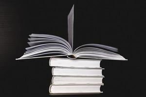 un' pila di bianca vuoto libri su un' mensola su un' nero sfondo, gratuito spazio per copiando, senza etichette, un vuoto colonna vertebrale. foto