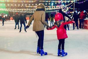 contento famiglia all'aperto ghiaccio pattinando a pista madre e figlia ha inverno attività mamma bambini foto