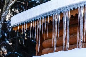ghiaccioli sospeso a partire dal il di legno tetto, creativo inverno sfondo foto