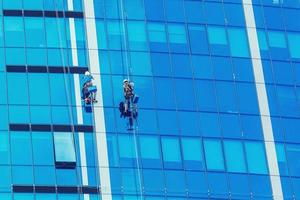 Due lavoratori lavaggio finestre di il moderno costruzione. foto