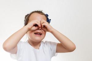 poco ragazza guardare attraverso immaginario binoculare, isolato su bianca foto