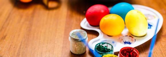 multicolore Pasqua dipinto fatto a mano uova, vernici e spazzole. festivo Pasqua telaio a partire dal uova, vernici e spazzole su bianca di legno sfondo con spazio per testo foto