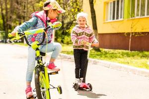 bambini che imparano a guidare una bicicletta su un vialetto fuori. bambine in sella a biciclette su strada asfaltata in città foto