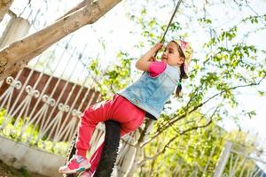 contento poco ragazza giocando swing a parco foto