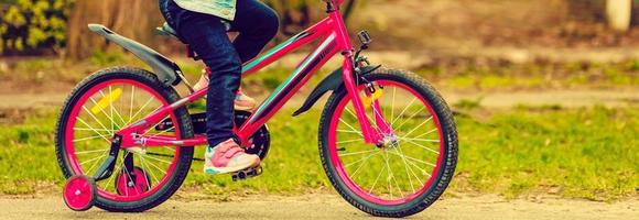 avvicinamento dettaglio di poco ragazza bambino piedi su un' bambino bicicletta foto