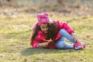 un' poco ragazza è pianto a voce alta nel il primavera foresta. lei si siede su il erba e caduto le foglie. lei si apre sua bocca largo e urla. su il viso emozioni di disperazione e risentimento foto