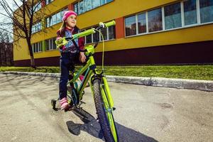 bellissimo sorridente poco ragazza equitazione bicicletta foto