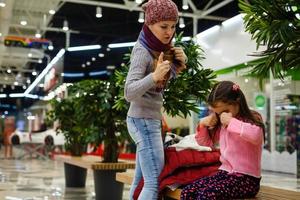 poco ragazza grida e madre rimprovera a il centro commerciale foto