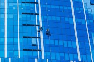 Due lavoratori lavaggio finestre di il moderno costruzione. foto