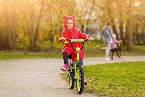 bellissimo sorridente poco ragazza equitazione bicicletta nel un' parco foto