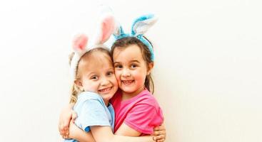 Due carino poco sorelle indossare coniglietto orecchie giocando uovo caccia su Pasqua. adorabile bambini celebrare Pasqua a casa. foto