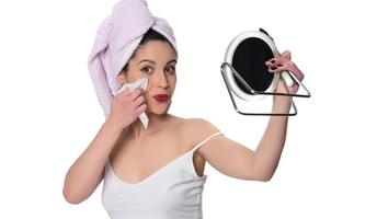 donna pulizia rimozione trucco a partire dal sua viso con un' bagnato tovagliolo foto