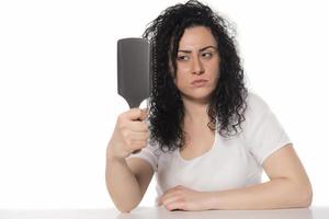 giovane donna provando per pettine sua Riccio capelli foto