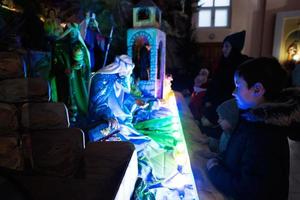 madre con tre bambini visitare Natale Natività culla scena nel Chiesa. foto