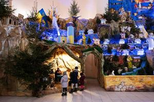 indietro di tre bambini guardare nel Natale Natività culla scena nel Chiesa. foto