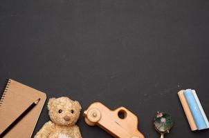 Marrone orsacchiotto orso, di legno giocattolo auto e bicchiere globo su nero gesso asse, indietro per scuola foto