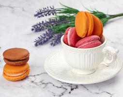 al forno macarons nel un' bianca ceramica tazza su il tavolo foto