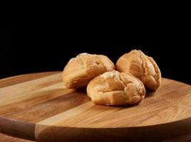 al forno crema pasticciera eclairs e cosparso con in polvere zucchero su un' Marrone di legno tavola foto