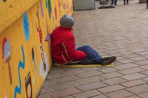 bratislava, slovacchia - 01.07.2023 senza casa povero uomo si siede su il marciapiede su il città strada. foto